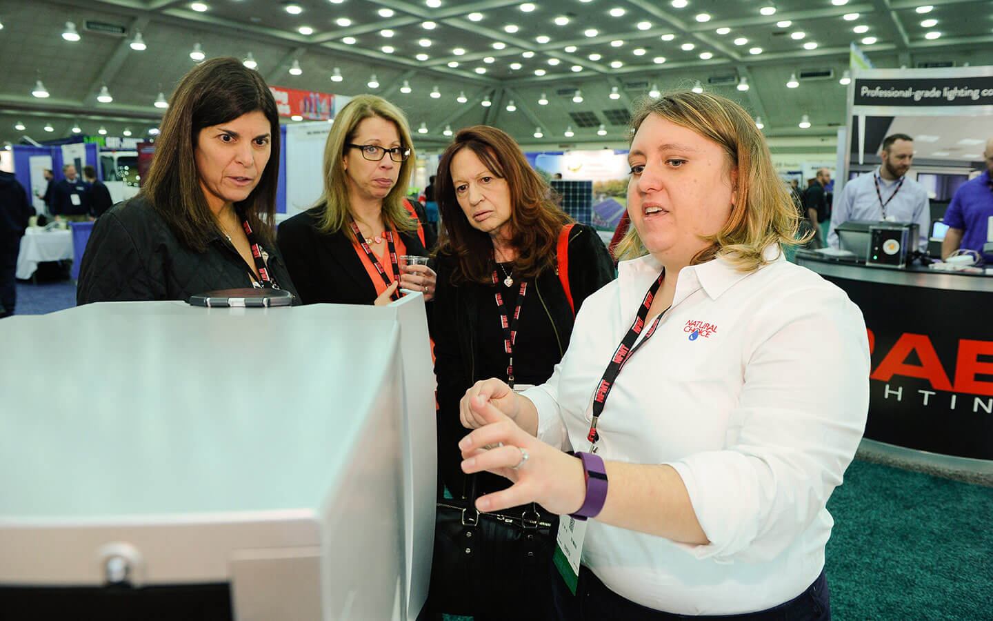 NFMT exhibitor showing product to group of women