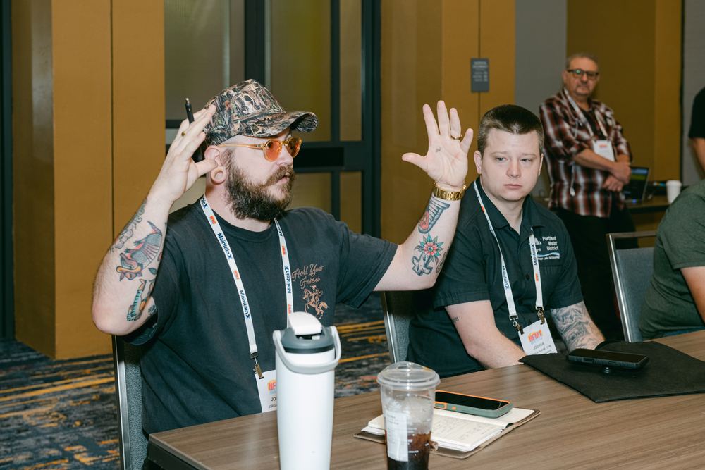 An attendee raises his hands while asking a question during a roundtable discussion
